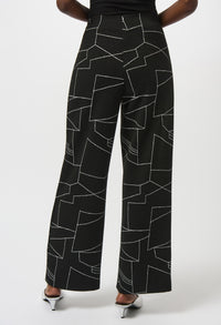 Black pants with white geometric pattern worn by a person on a white background