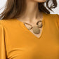 Woman wearing a mustard yellow top with a necklace on a white background