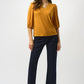 Woman wearing a mustard yellow top and navy pants on a white background