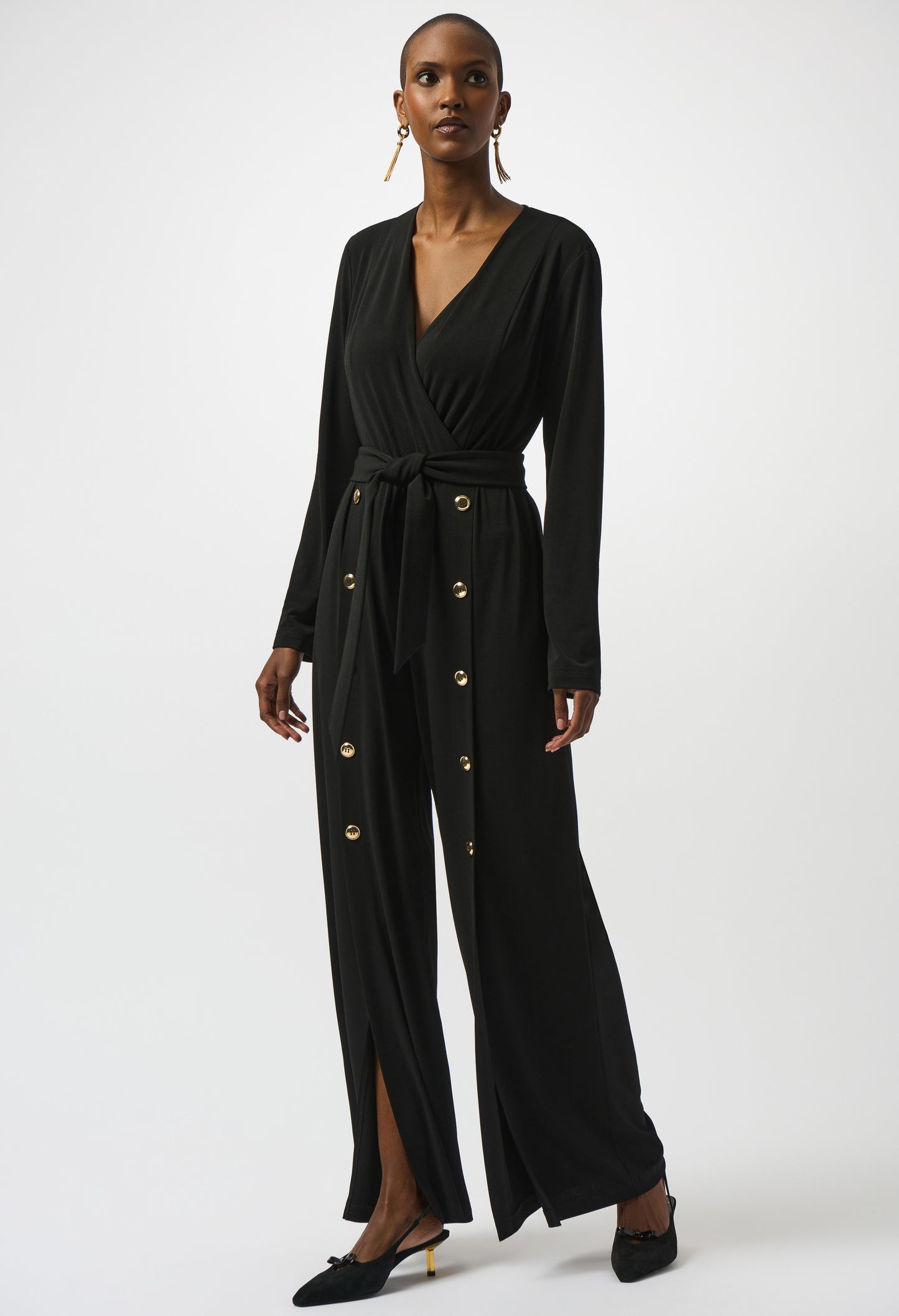 Woman wearing a black jumpsuit with gold buttons on a white background