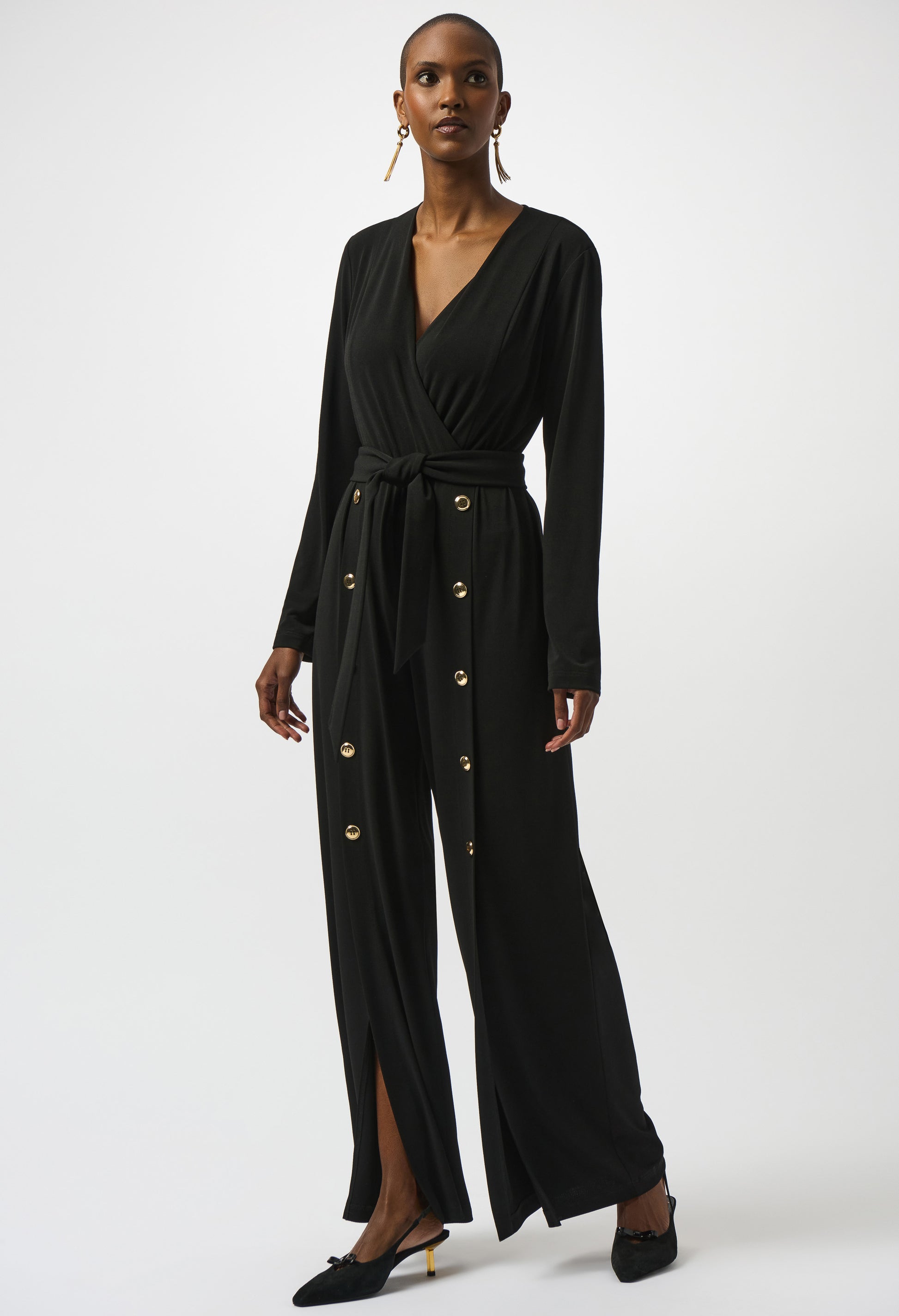 Woman wearing a black jumpsuit with gold buttons on a white background