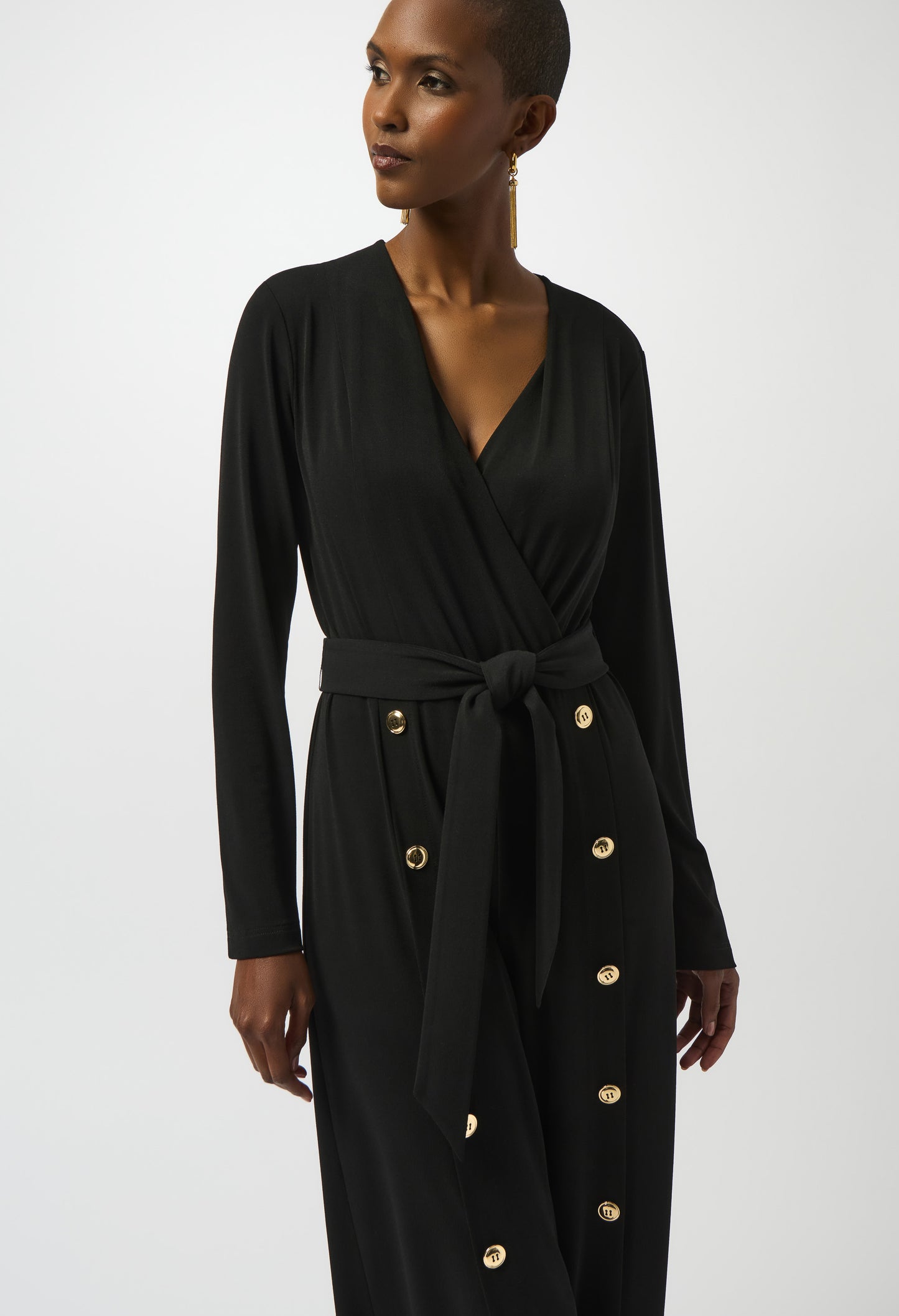Woman wearing a black dress with gold buttons on a white background