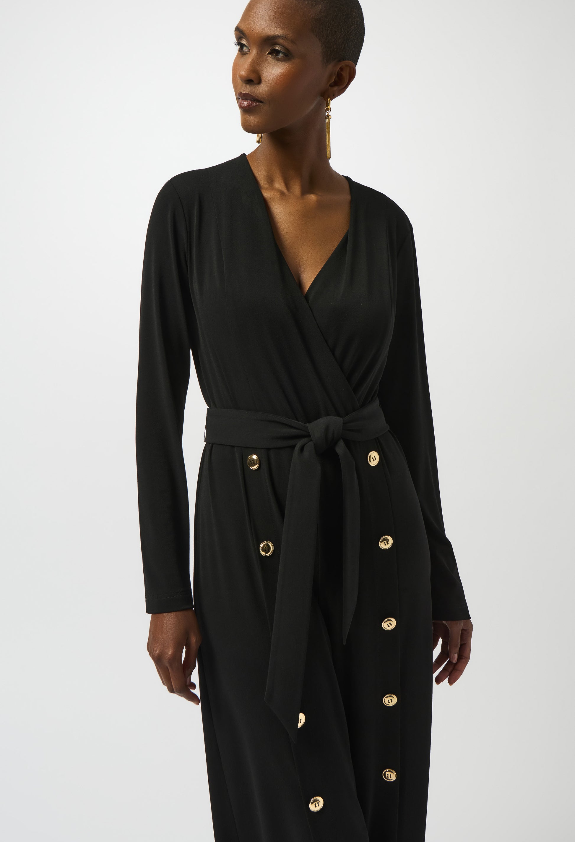 Woman wearing a black dress with gold buttons on a white background