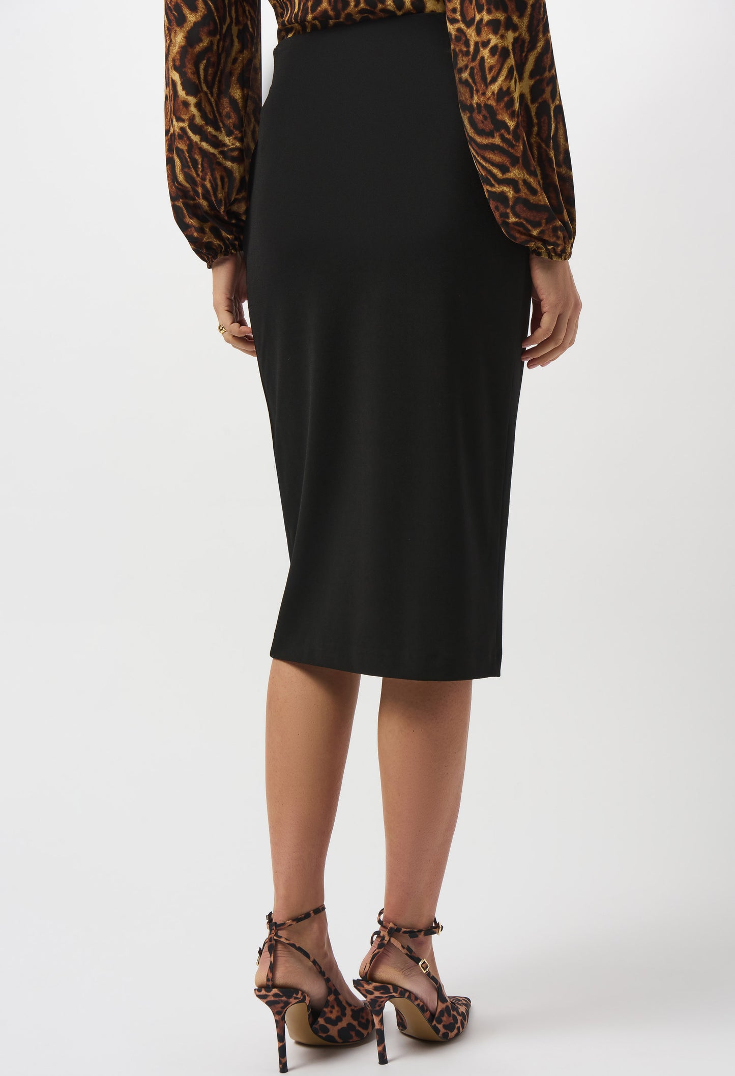 Person wearing a black pencil skirt with leopard print top and shoes on a white background