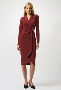 Woman wearing a burgundy dress with a belt on a white background