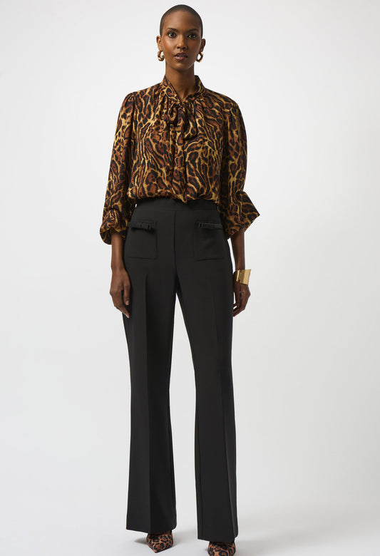 Person wearing a leopard print blouse and black pants on a white background