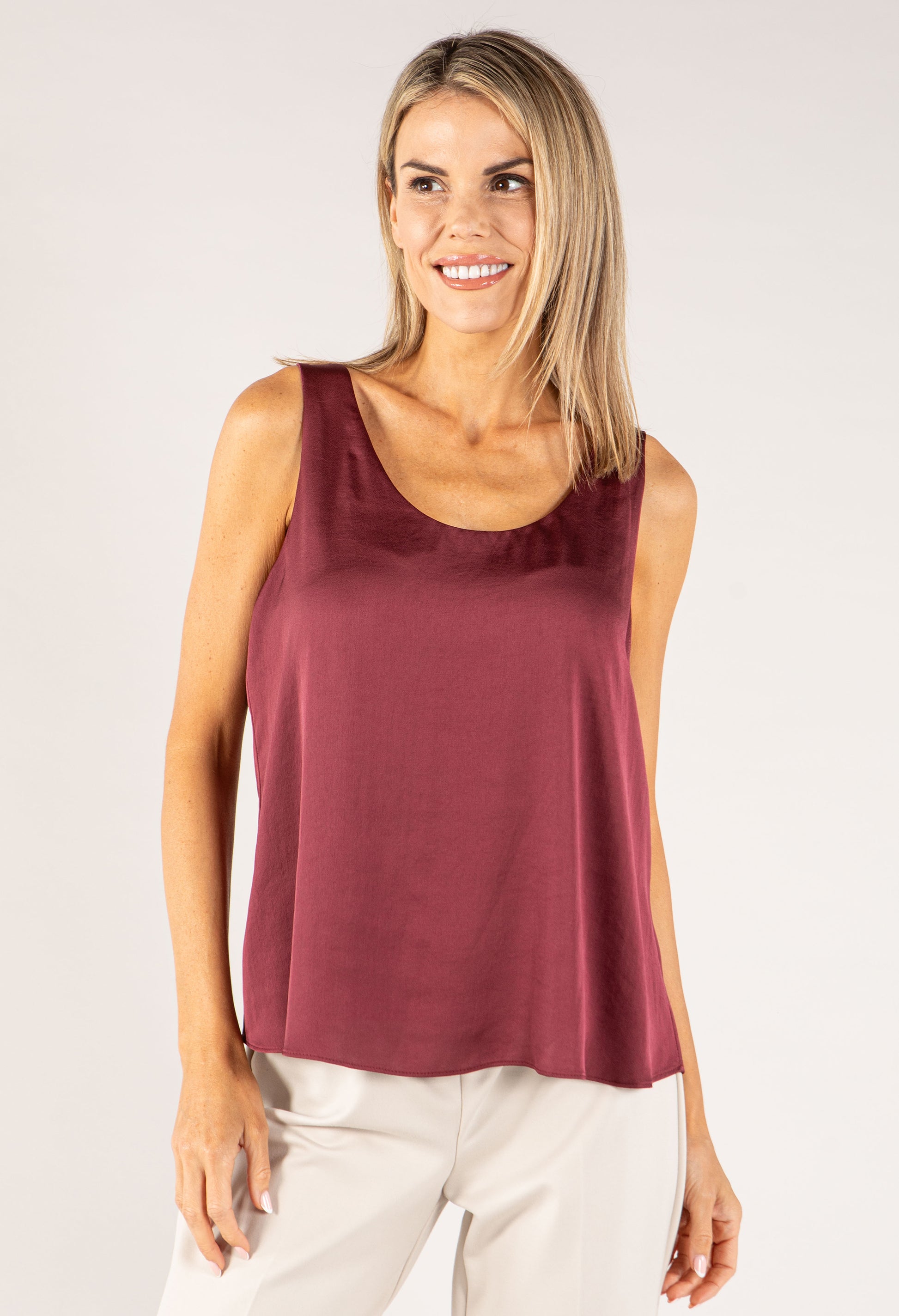 Woman wearing a burgundy sleeveless top against a plain background