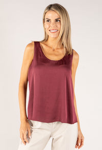 Woman wearing a burgundy sleeveless top against a plain background