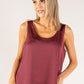 Woman wearing a burgundy tank top against a plain background