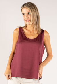 Woman wearing a burgundy tank top against a plain background