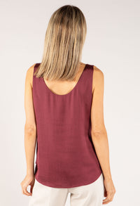 Person wearing a maroon sleeveless top on a plain background