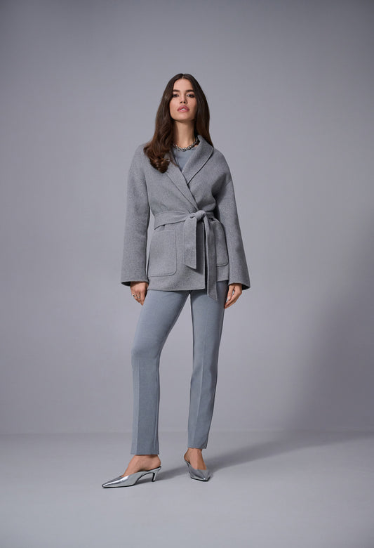 Woman wearing a gray suit standing against a plain background