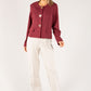 Woman wearing a burgundy blazer and white pants on a white background