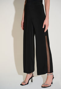 Black wide-leg pants with mesh side panels worn by a person on a white background