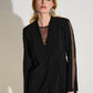 Woman wearing a black blazer with sheer sleeves against a white background