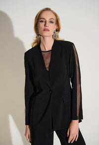 Woman wearing a black blazer with sheer sleeves against a white background