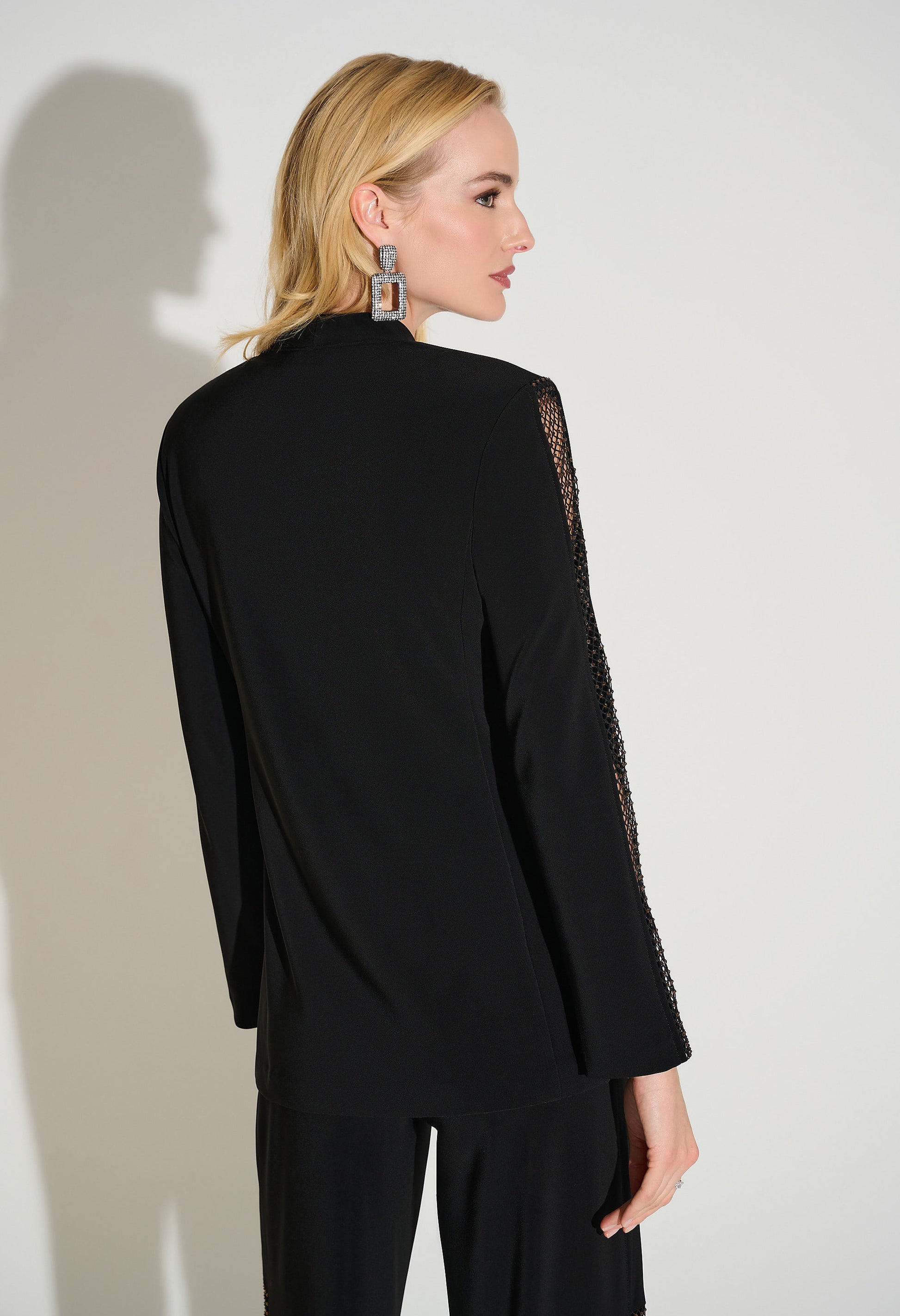 Woman wearing a black outfit with lace sleeves against a white background