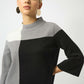Woman wearing a gray and black color-blocked sweater on a white background