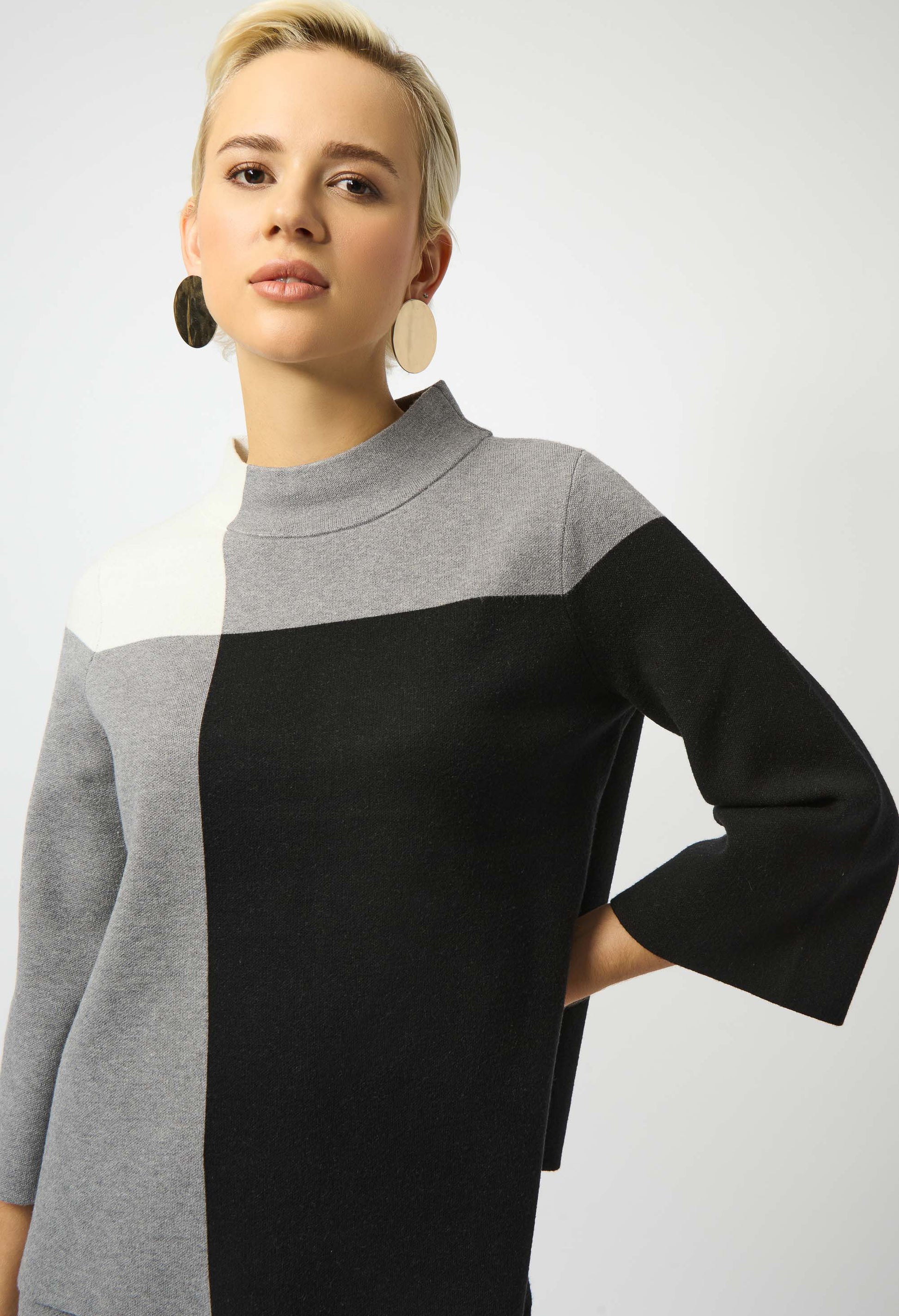 Woman wearing a gray and black color-blocked sweater on a white background