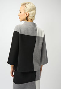 Person wearing a black, gray, and white color-blocked outfit on a plain background