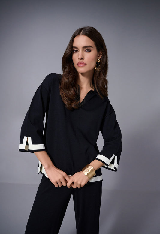 Woman wearing a black outfit with white accents on a gray background