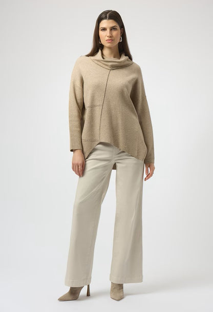 Woman wearing a beige cowl-neck sweater and cream trousers on a white background