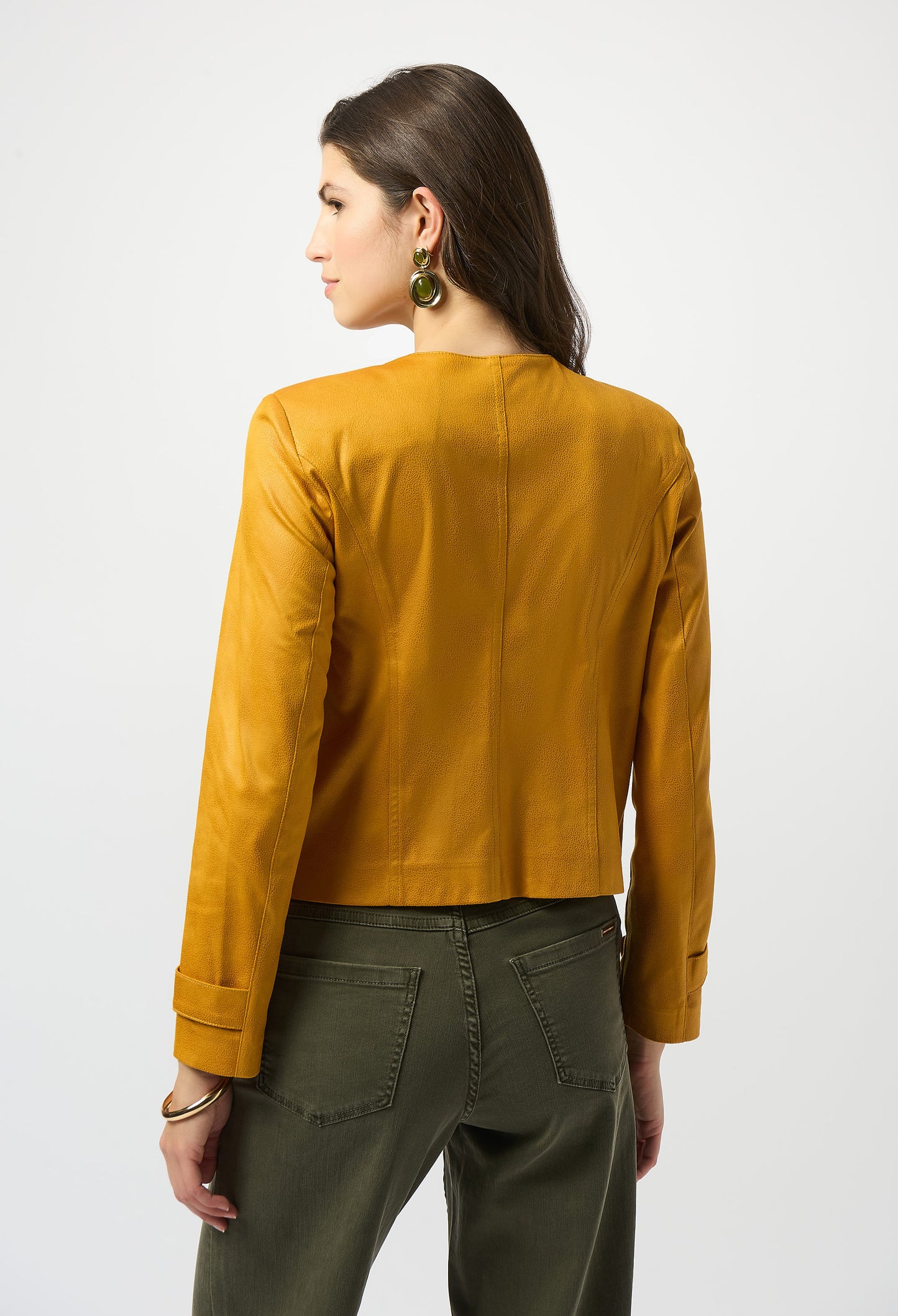 Woman wearing a mustard yellow jacket and green pants on a white background