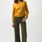 Woman wearing a mustard yellow blouse and olive green pants on a white background