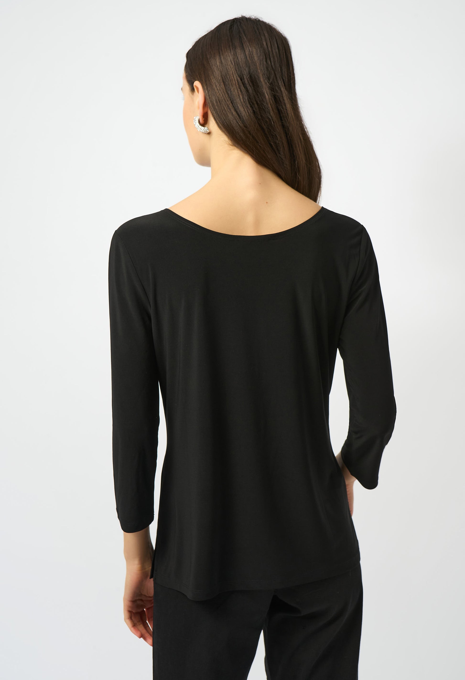 Woman wearing a black long-sleeve top and pants on a white background