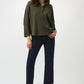 Woman wearing a green sweater and black pants on a white background