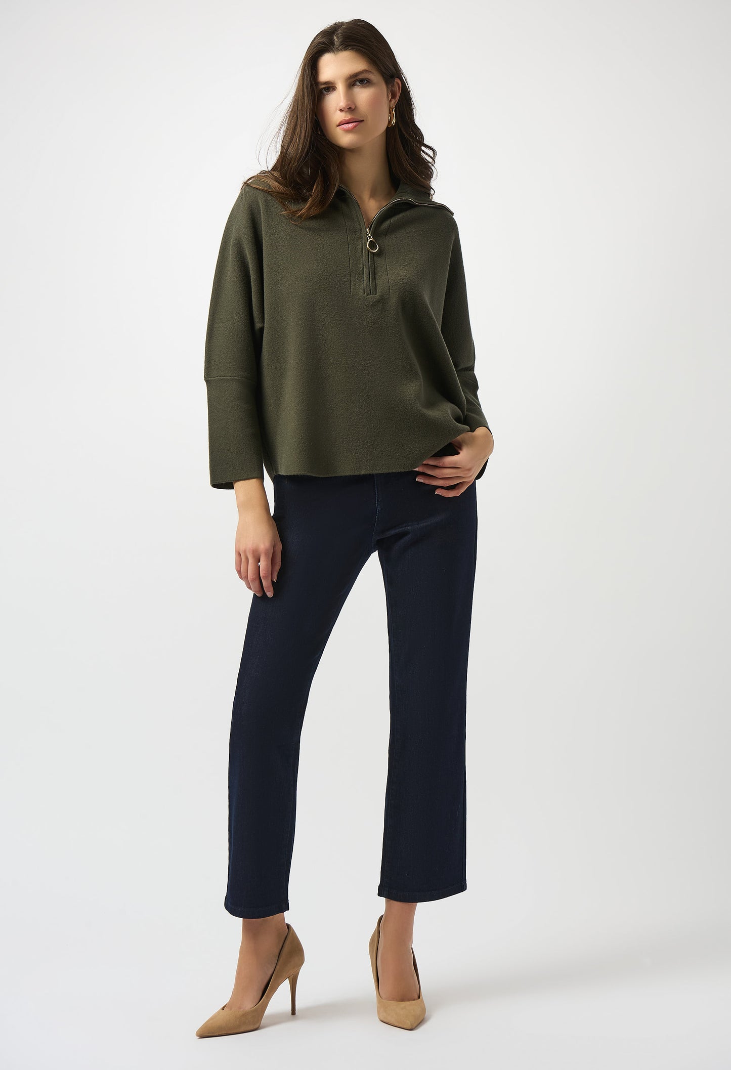 Woman wearing a green sweater and black pants on a white background