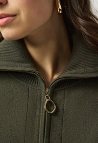 Close-up of a person wearing a green jacket with a gold zipper and earring.