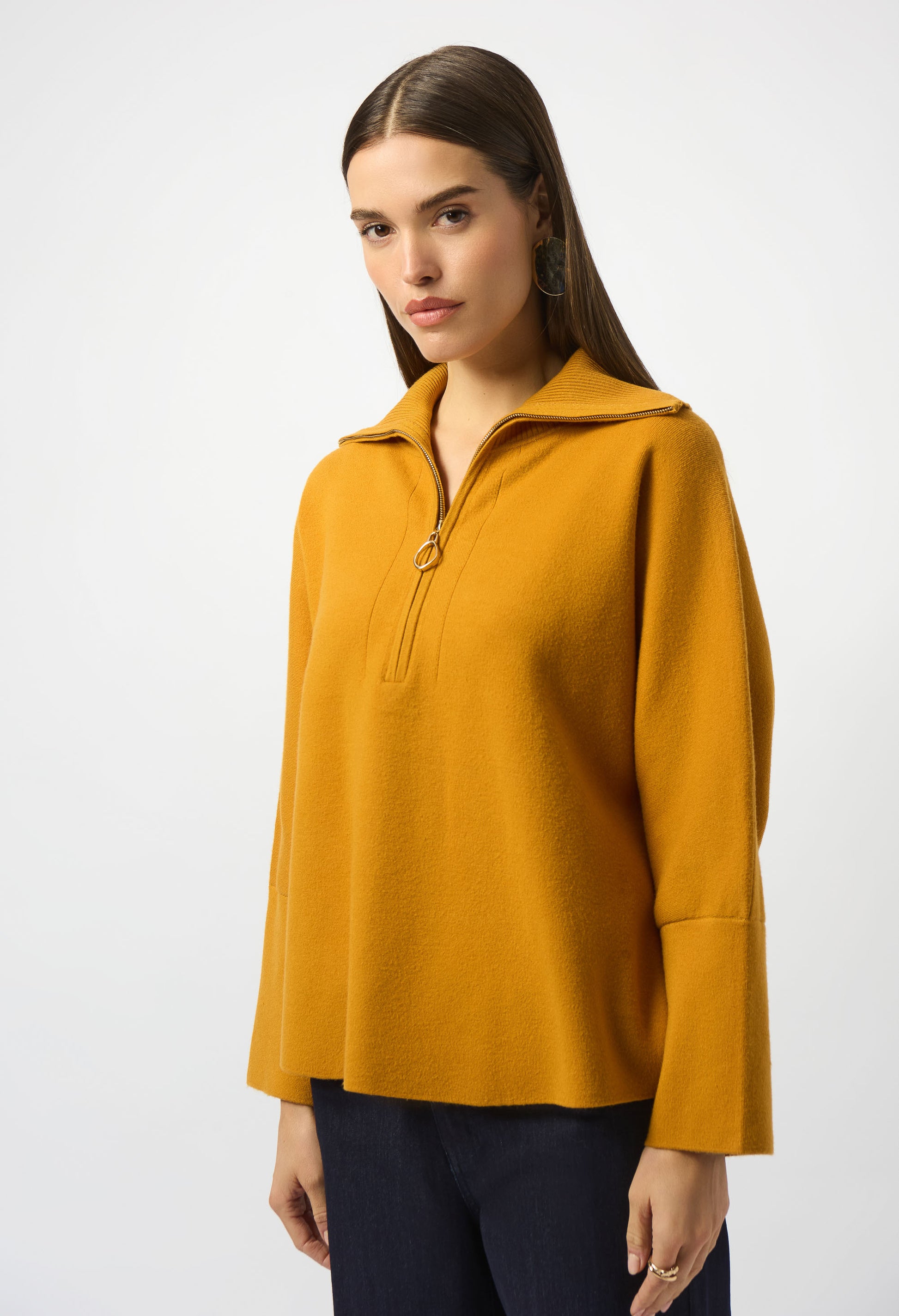 Woman wearing a mustard yellow long-sleeve top on a white background