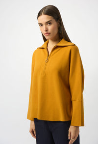 Woman wearing a mustard yellow long-sleeve top on a white background