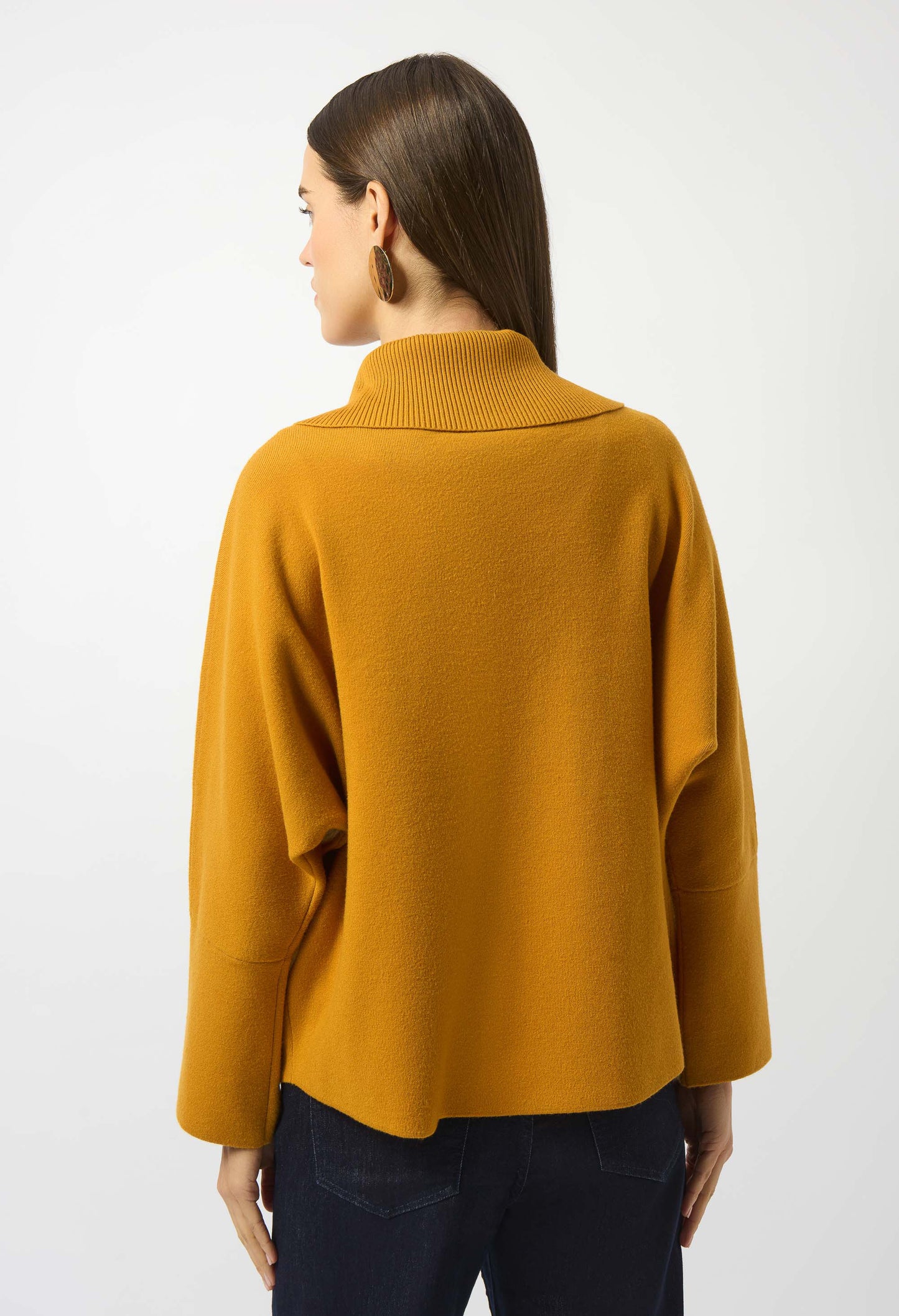 Person wearing a mustard yellow sweater on a white background