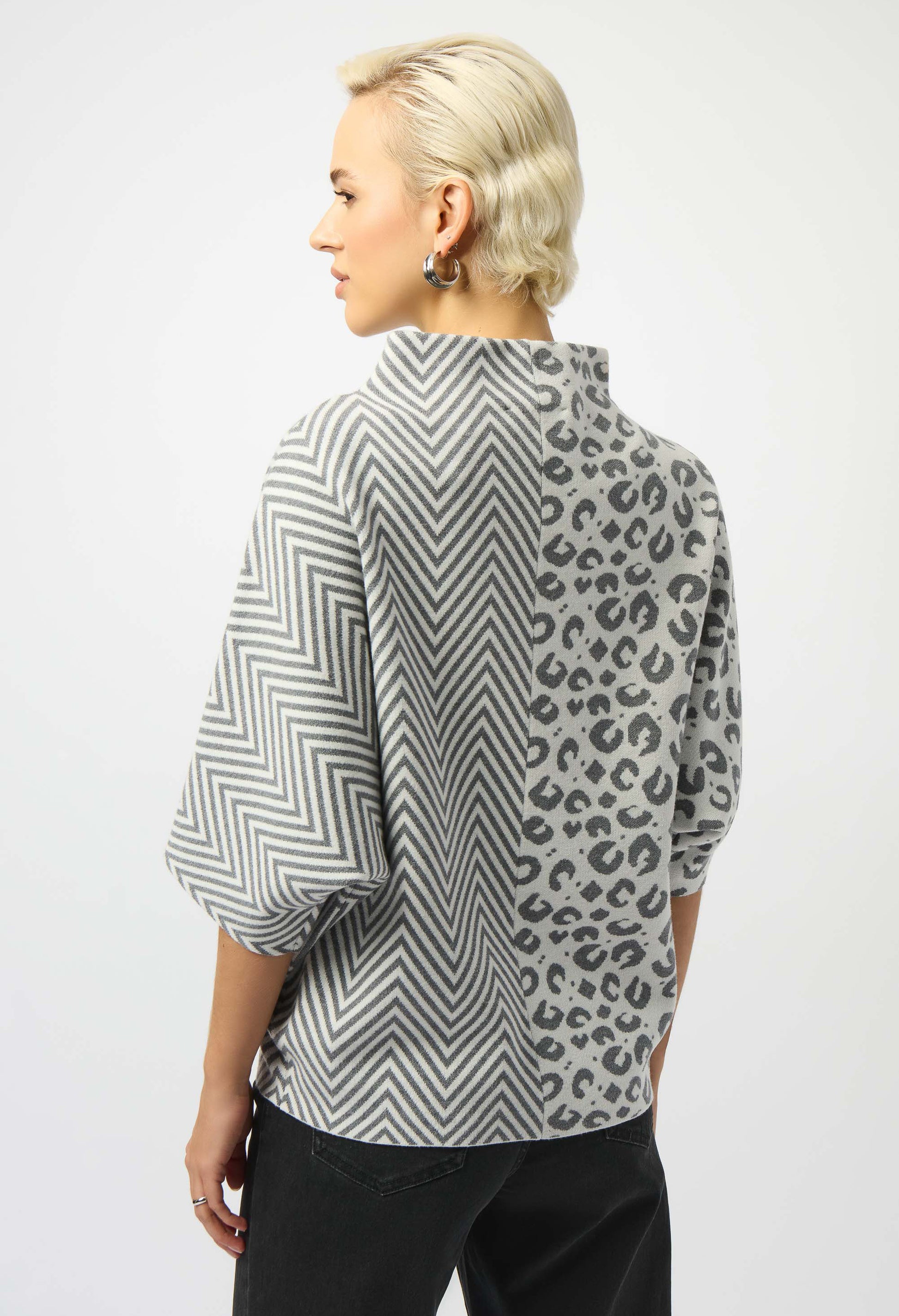 Person wearing a patterned shirt with chevron and leopard print on a white background
