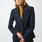 Woman wearing a navy blue blazer over a mustard yellow sweater on a white background