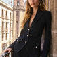 Woman in a black suit standing on a balcony with a cityscape background