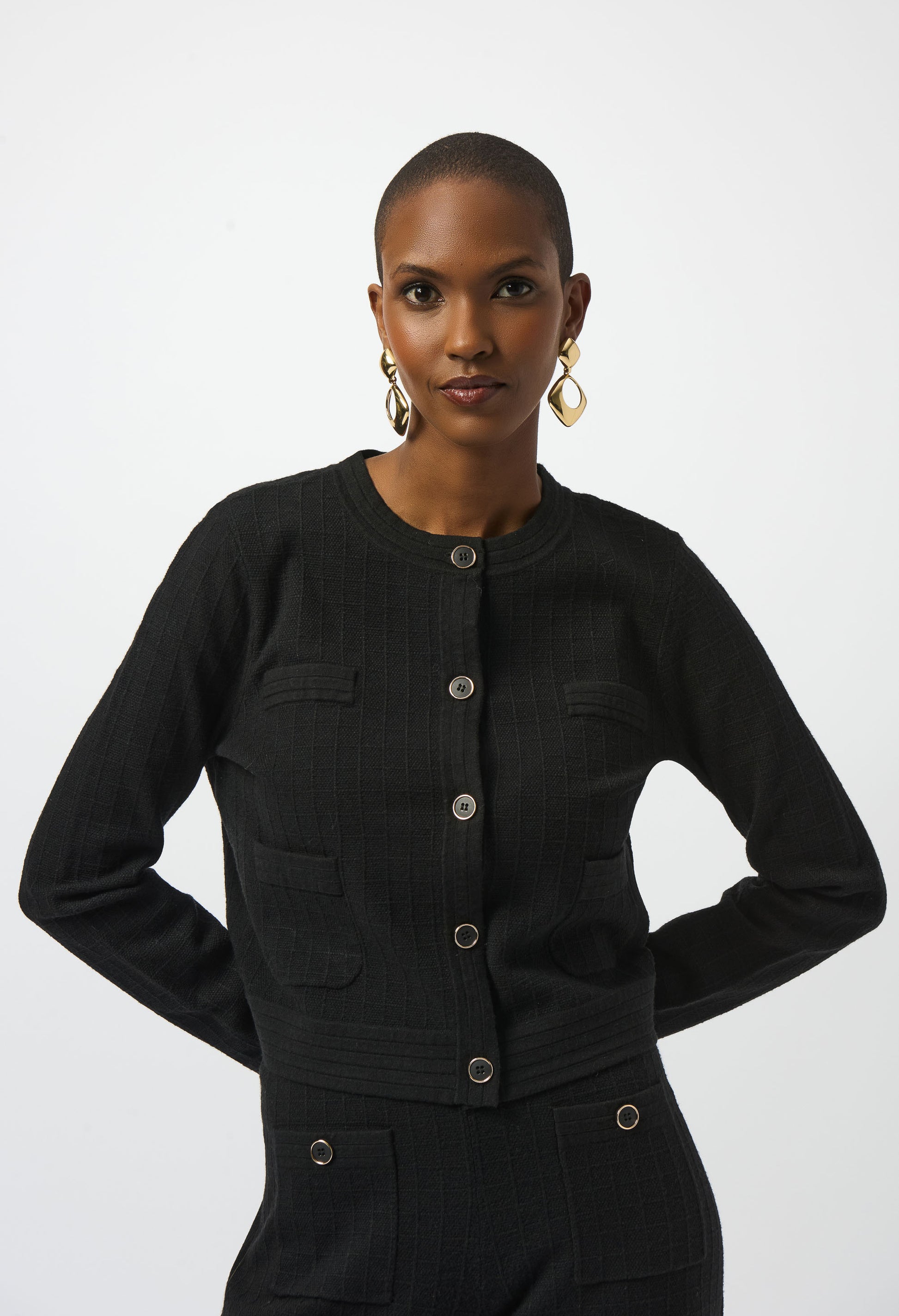 Woman wearing a black jacket with silver buttons on a white background