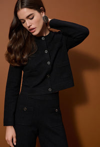 Woman wearing a black outfit against a brown background