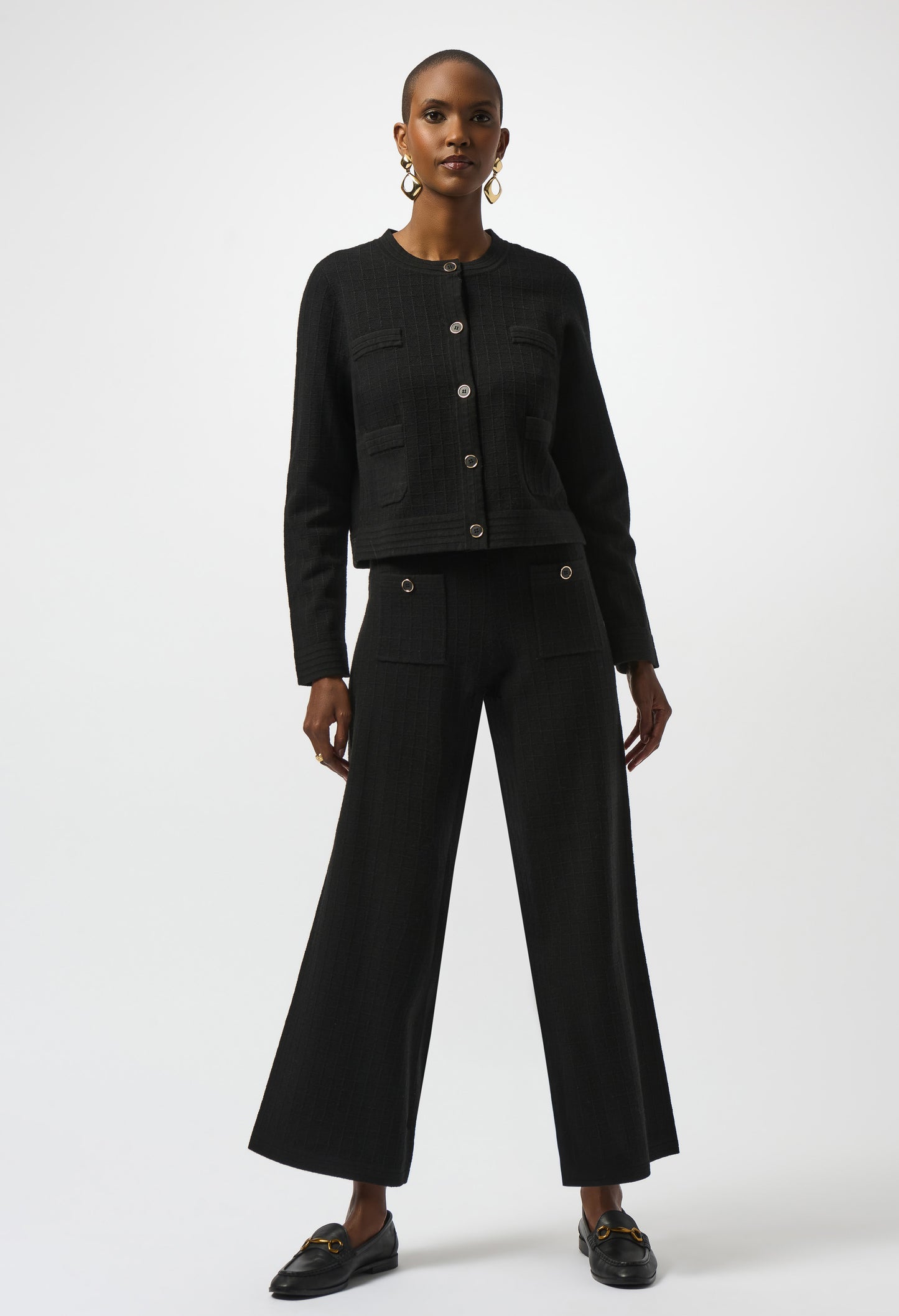Woman wearing a black outfit with wide-leg pants on a white background