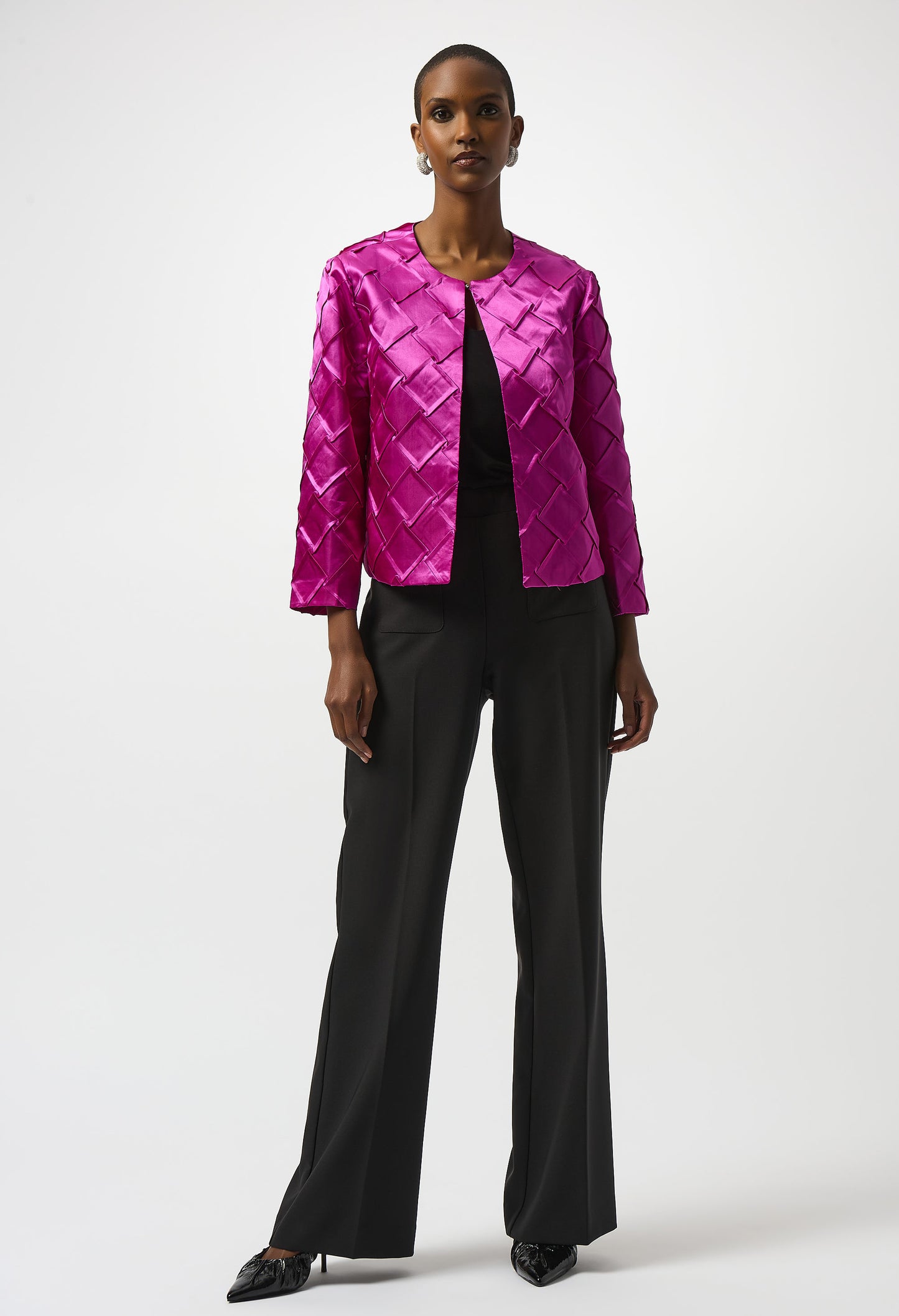 Person wearing a bright pink quilted jacket and black pants on a white background