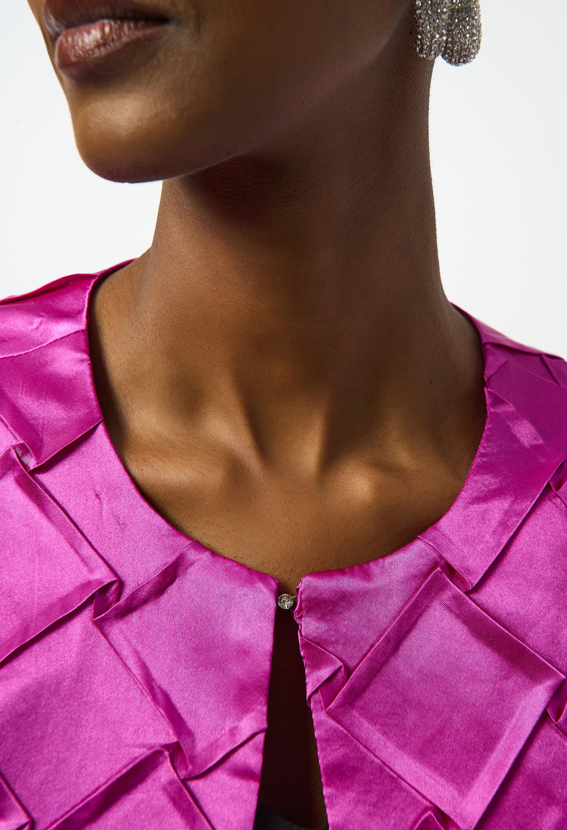 Close-up of a person wearing a bright pink satin top with a blurred background
