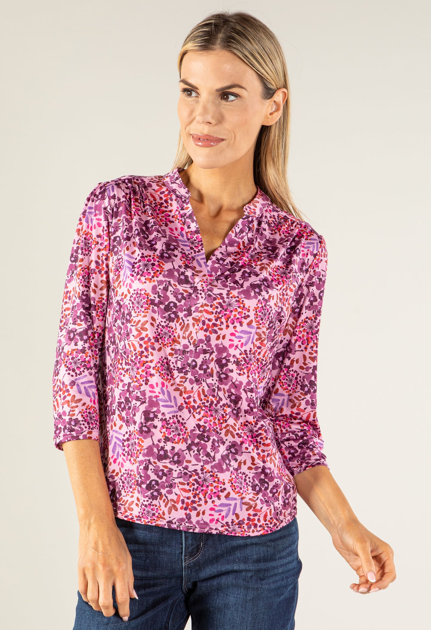 Woman wearing a pink floral blouse against a plain background