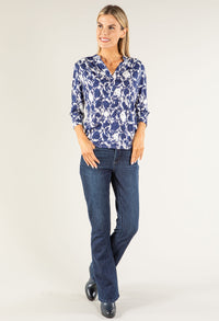 Woman wearing a blue floral blouse and jeans on a white background