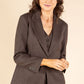 Woman wearing a brown suit against a beige background