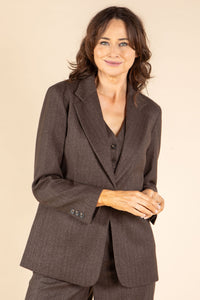 Woman wearing a brown suit against a beige background