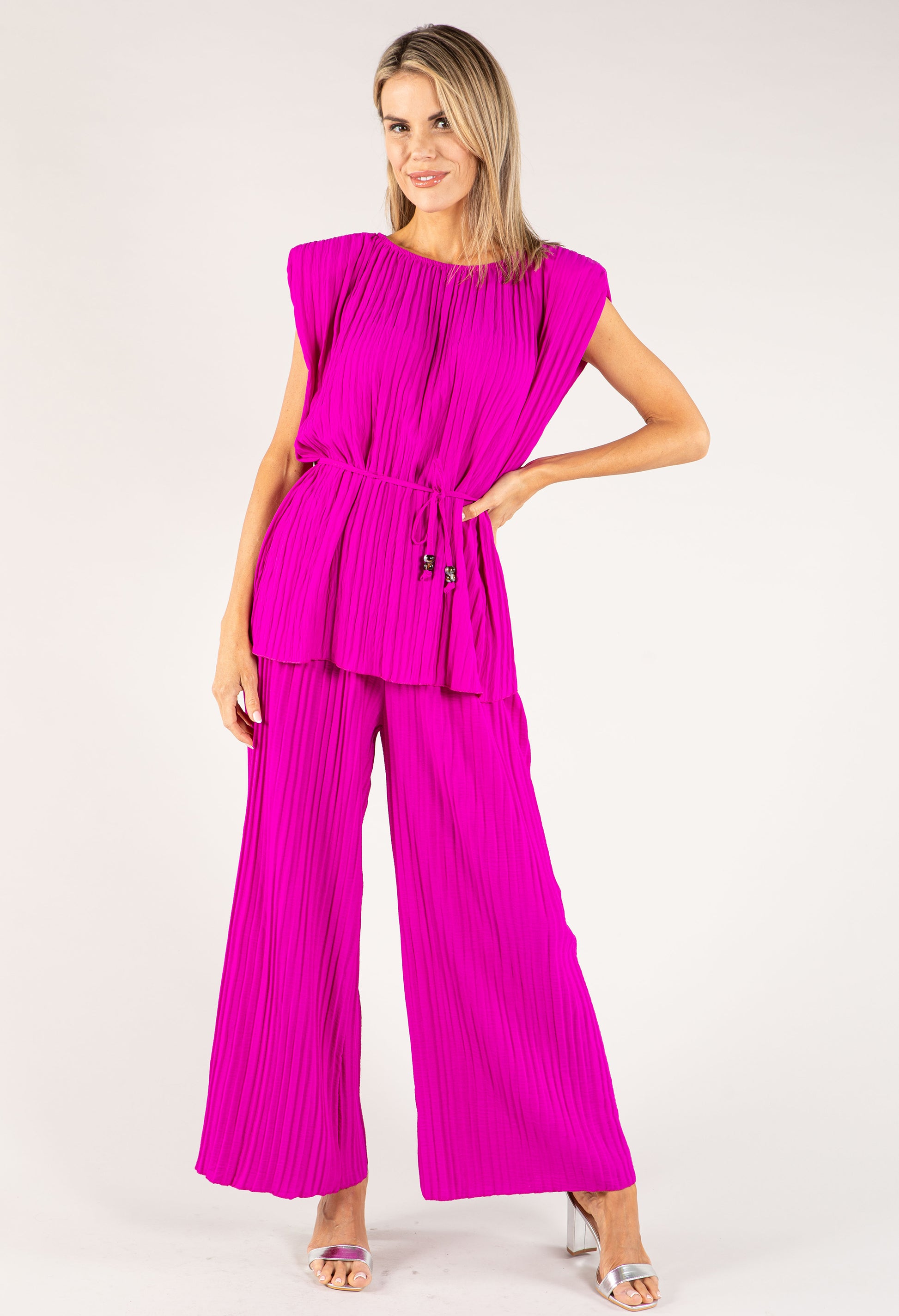 Woman wearing a bright pink jumpsuit on a white background