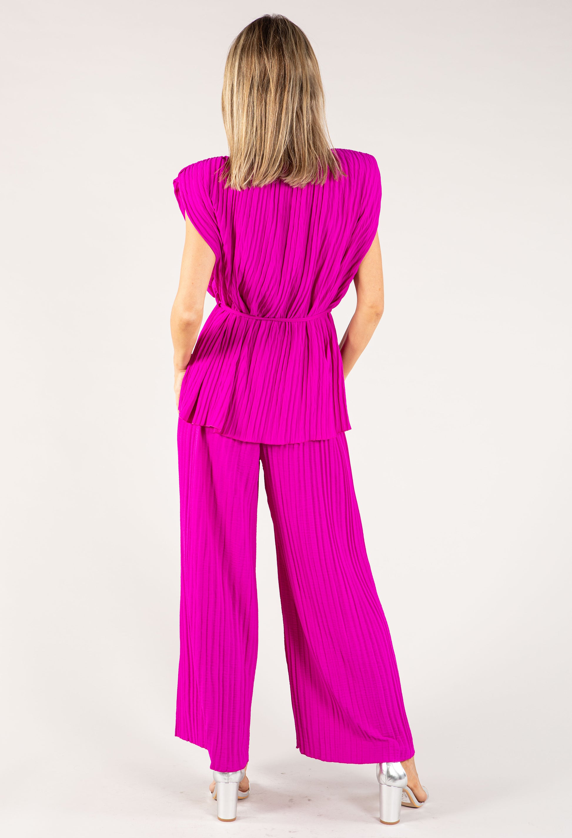 Woman wearing a bright pink pleated outfit on a white background