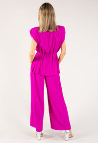 Woman wearing a bright pink pleated outfit on a white background